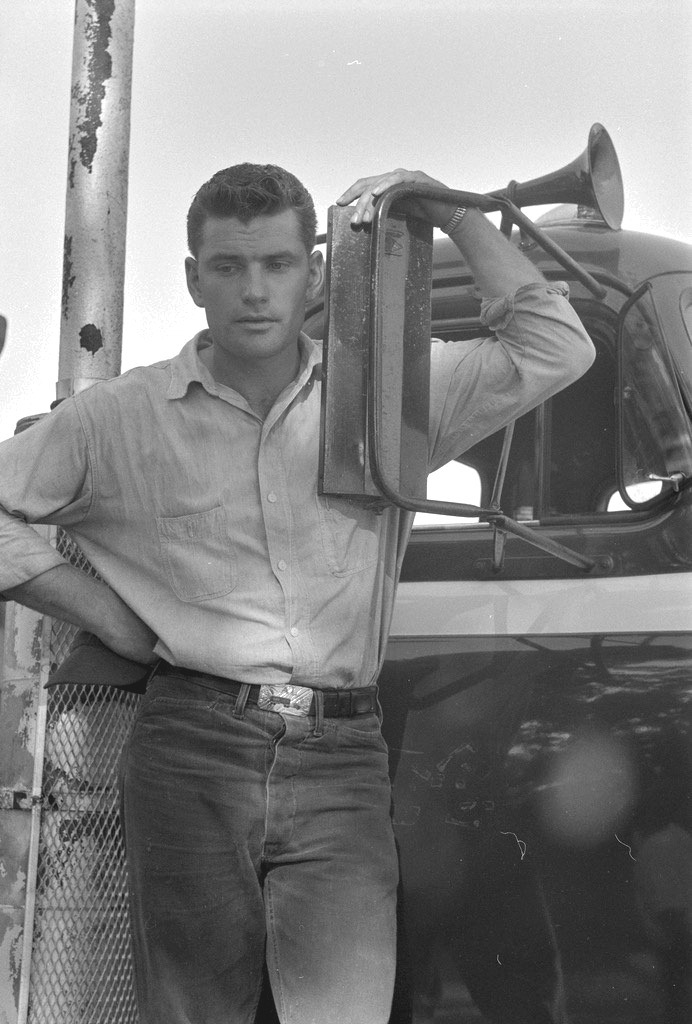 A young man leaning against a truck